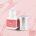 Cosmetic bottle with pink label and silver cap on a white background