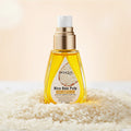 BIOAQUA Rice Raw Pulp oil bottle with a hand applying oil, white flowers in the background