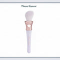 Makeup brush with decorative handle on a light blue background, featuring the brand 'Flower Knows'.