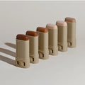Set of beige makeup sticks with brown caps on a light gray background