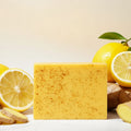 Sadoer Turmeric Lemon Kojic Acid Soap Bar with packaging, lemons, and ginger on a light background